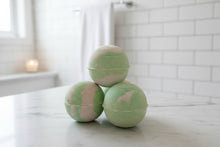 Load image into Gallery viewer, Stack of green and cream bath bombs on a bathroom counter