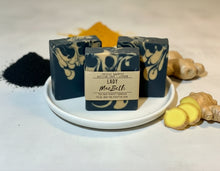 Load image into Gallery viewer, Three bars of soap with decorative swirls on a white plate, surrounded by turmeric and ginger on a light background.