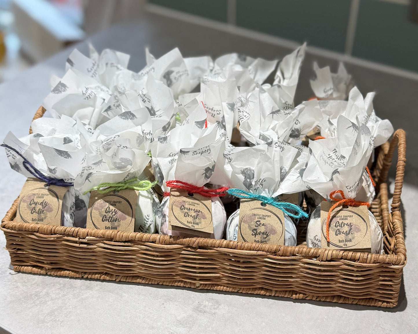 Basket of wrapped bath bombs with labels on a light surface