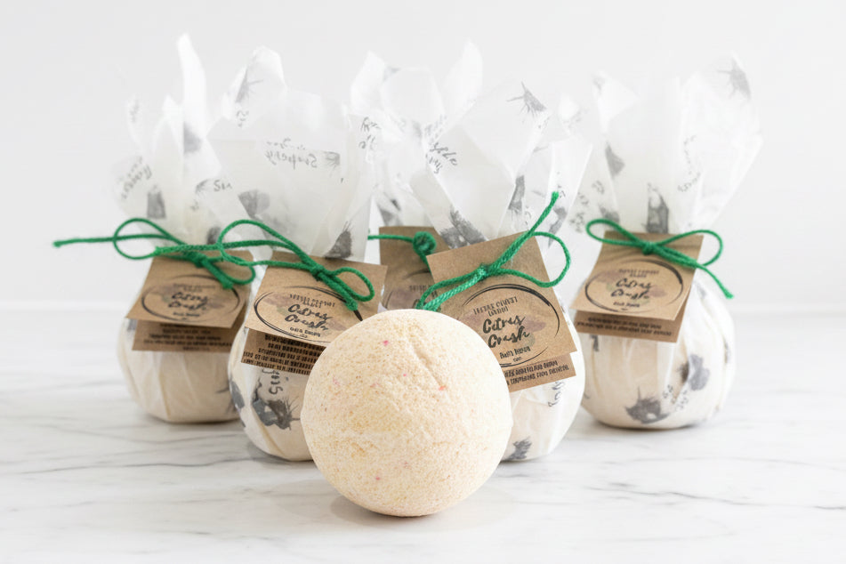 Pale orange bath bomb with beautifully packaged bath bombs in the background 