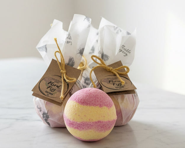 Yellow and pink swirled bath bomb with beautifully wrapped bath bombs in the background 