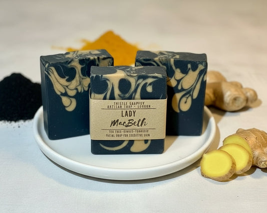 Three bars of soap with decorative swirls on a white plate, surrounded by turmeric and ginger on a light background.