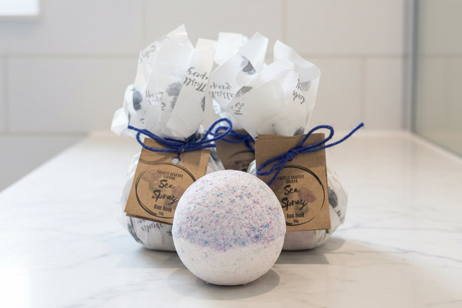 Blue and white bath bomb with beautifully wrapped bath bombs in the background 