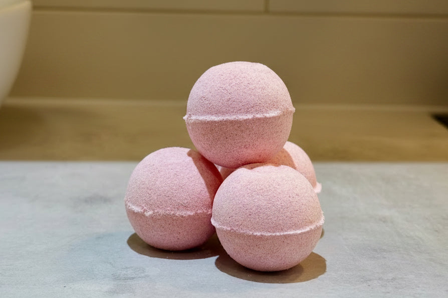 Pale pinky red Spicy Raspberry bath bombs stacked on a countertop 