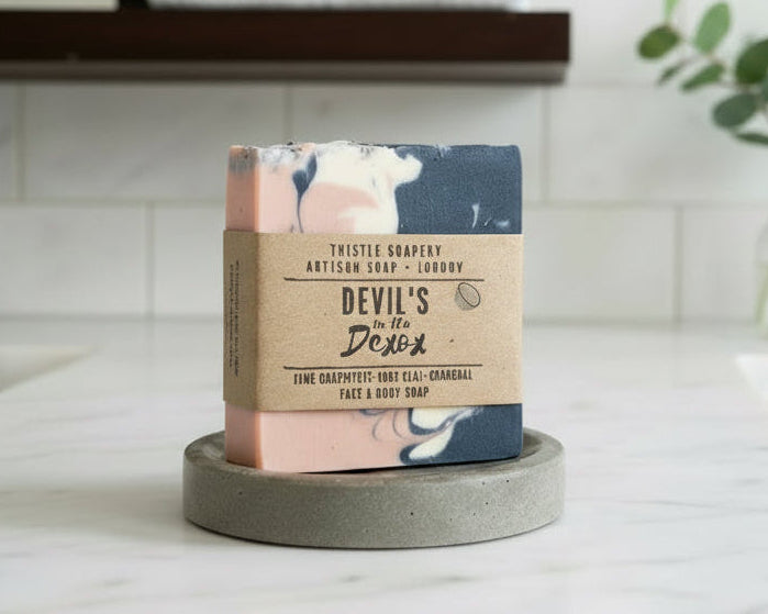 Pink, dark grey and white swirled soap on a soap dish 