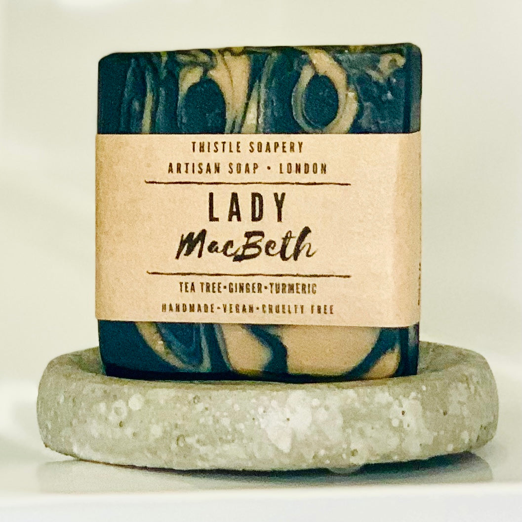 Thistle Soapery Handmade Vegan Facial Soap. Solid black soap bar with with turmeric soap swirls. Wrapped in a recycled kraft paper sleeve.
